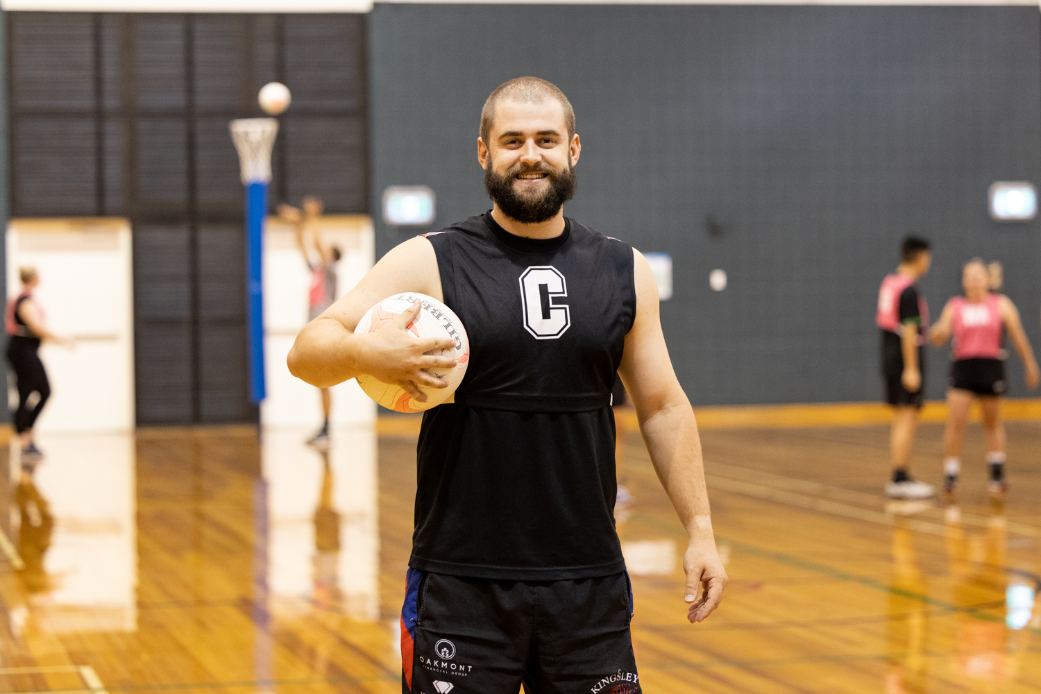 Happy mixed netball player standing mid-court with the netball